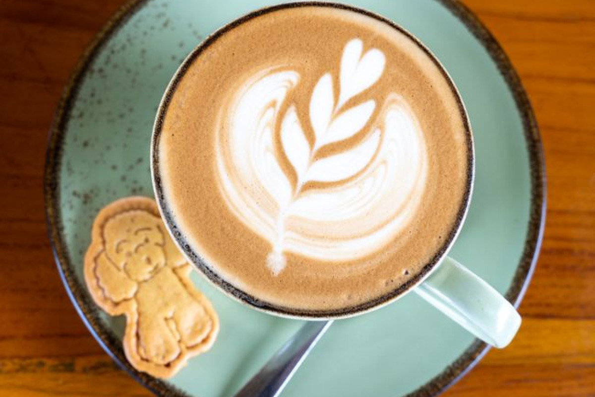 Un café au lait avec art décor et un biscuit en forme de chien, vue de dessus Un café au lait avec art décor et un biscuit en forme de chien, vue de dessus