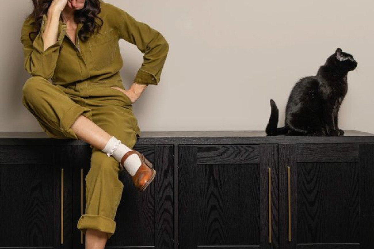 Une femme est assise avec un chat noir sur un buffet élégant, scène moderne et décontractée Une femme est assise avec un chat noir sur un buffet élégant, scène moderne et décontractée